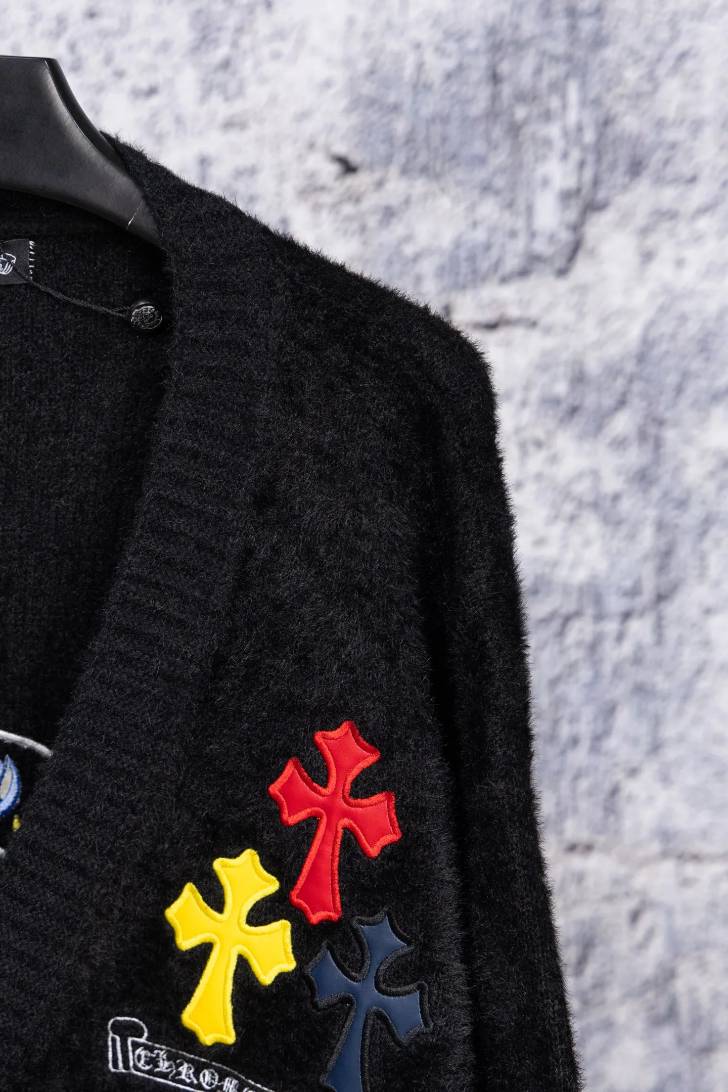 P300 Chrome Hearts CH Chrome Hearts 2026 new cross loose knitted V-neck cardigan Fabric: Made of plush textured knitted material, soft to the touch and with a lazy atmosphere; Decoration: Red, yellow, and black cross ornaments on the chest, paired with brand logo patches, which are iconic elements of street fashion brands (such as Chrome Hearts style), enhancing visual recognition; Version: Loose version + single-row metal button design, combining casual feeling and practicality. 2. Style and Adaptation Style: It combines dark street style and gentle knitted texture, which belongs to the tone of "sweet and cool mix"; Scenario: Can be worn with a T-shirt/suspender to create a daily street look, or can be layered with a shirt for light casual wear. Color: Black White Size: M L XL